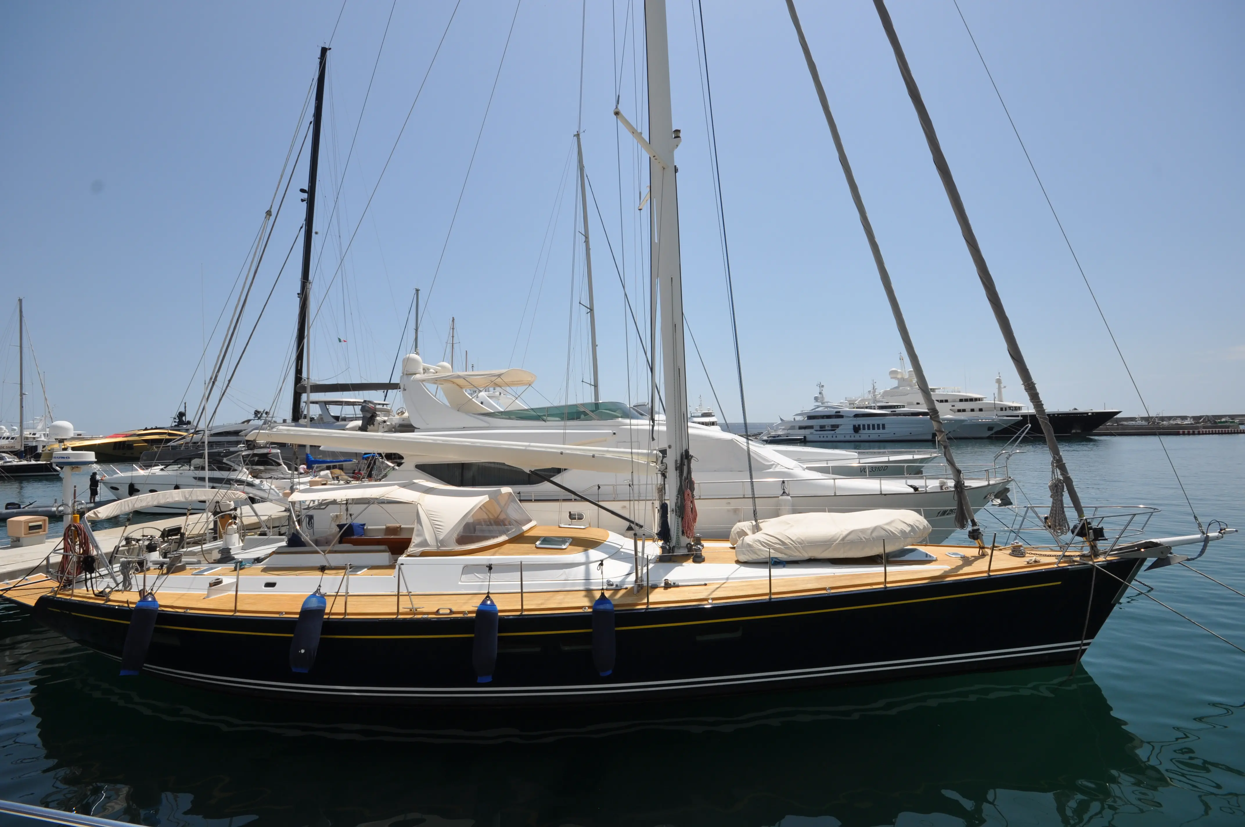 Cnb 70 — Voilier noir et bois amarré dans une marina, vu de profil.