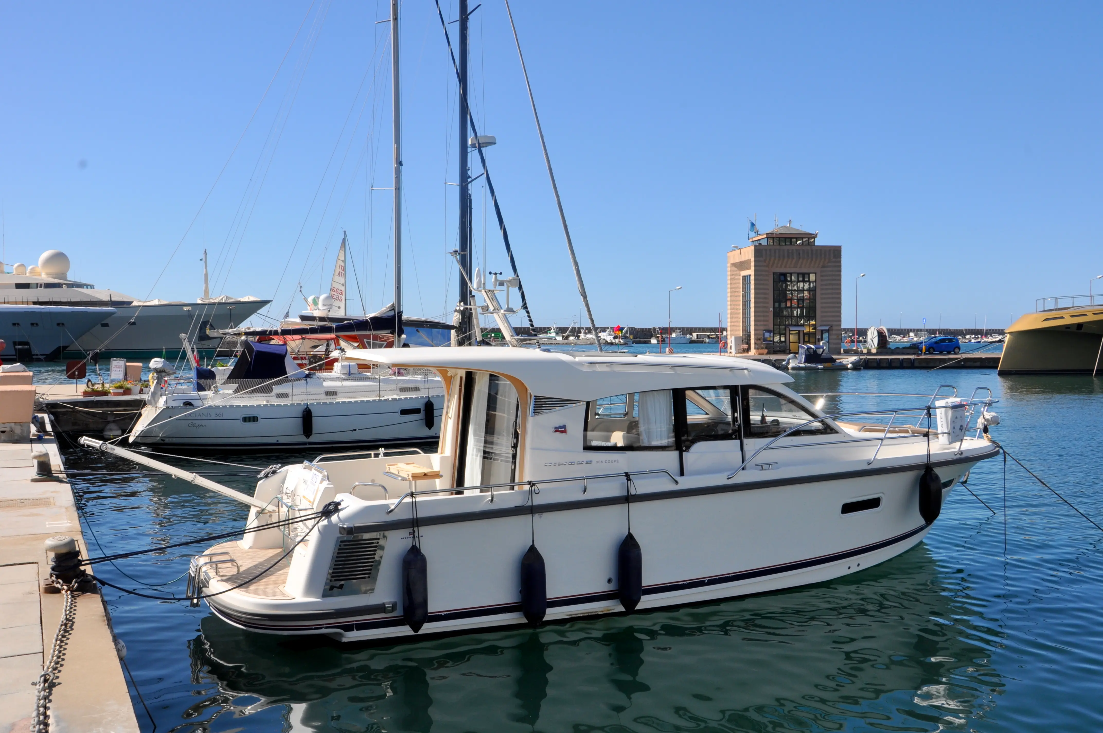 Nimbus 305 Coupe — Bateau à moteur blanc amarré dans un port, vu de trois quarts arrière.