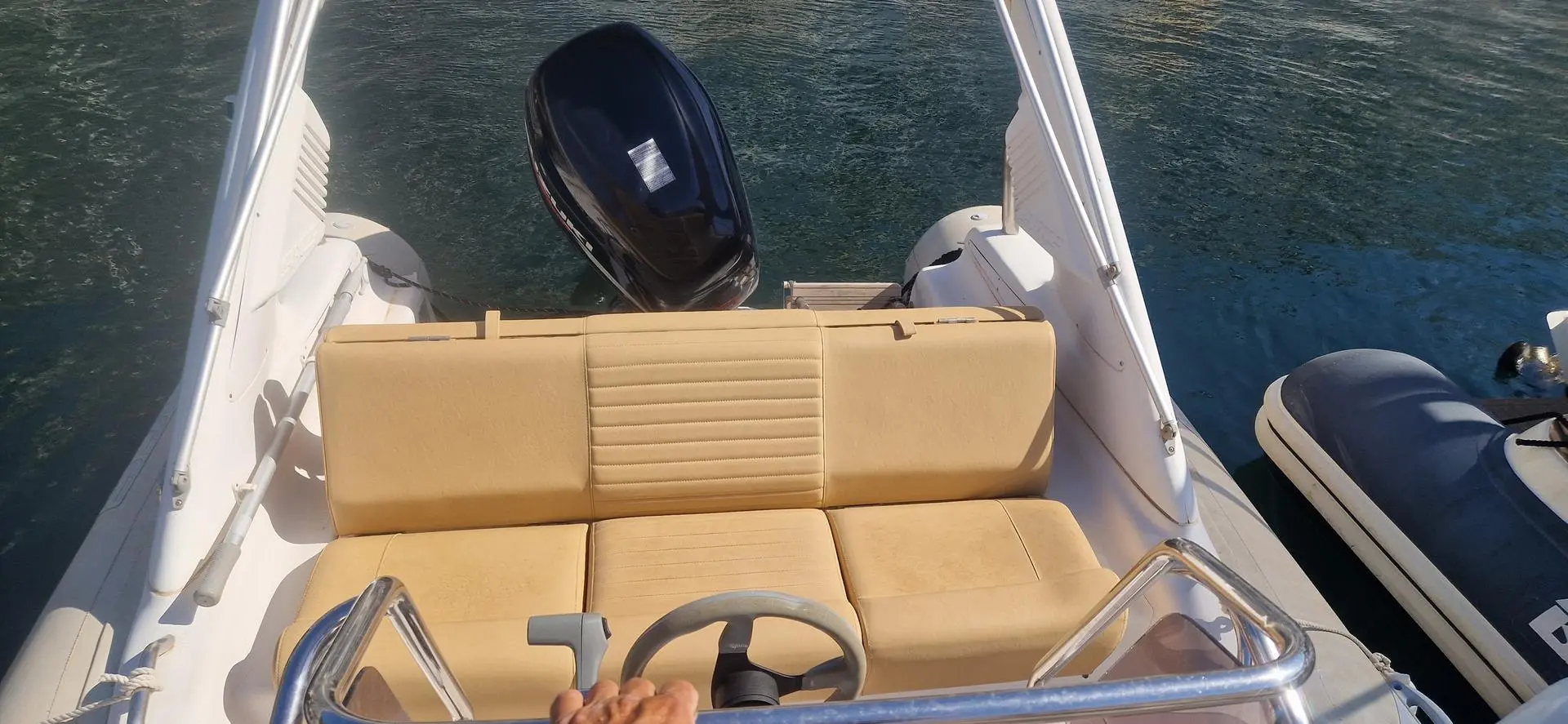 Sacs S 680 Ghost — Vue arrière du cockpit d’un bateau avec banquette, volant et moteur hors-bord.