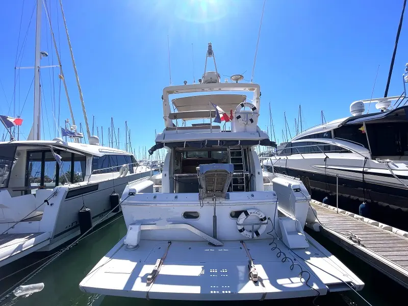 Ferretti Altura 45 Fly — Vue arrière d’un bateau blanc amarré dans une marina, avec passavants et flybridge.