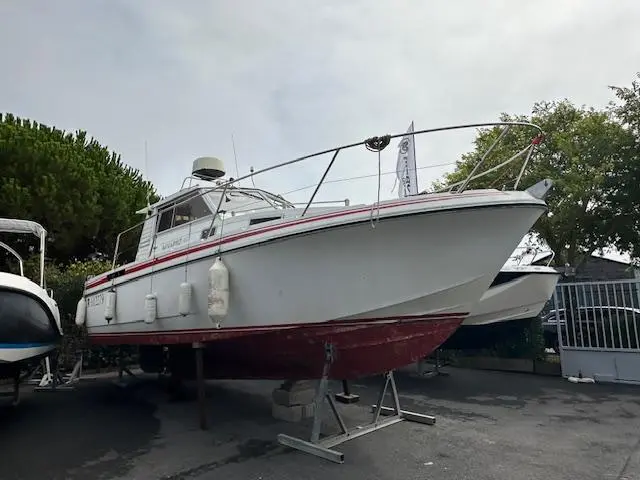 Beneteau Antares 860 — Bateau à moteur blanc et rouge présenté à terre sur bers, vu de trois quarts avant.