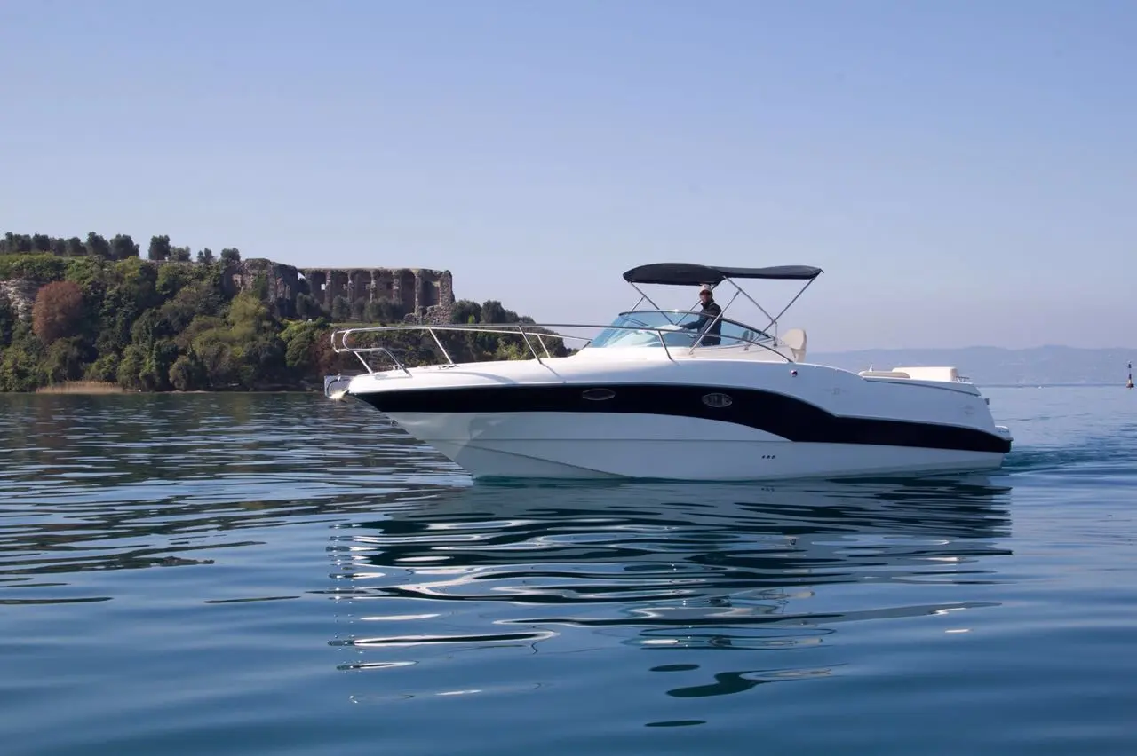 Rio Yachts 32 BLU — Bateau à moteur blanc et noir photographié sur une eau calme près d’une côte.