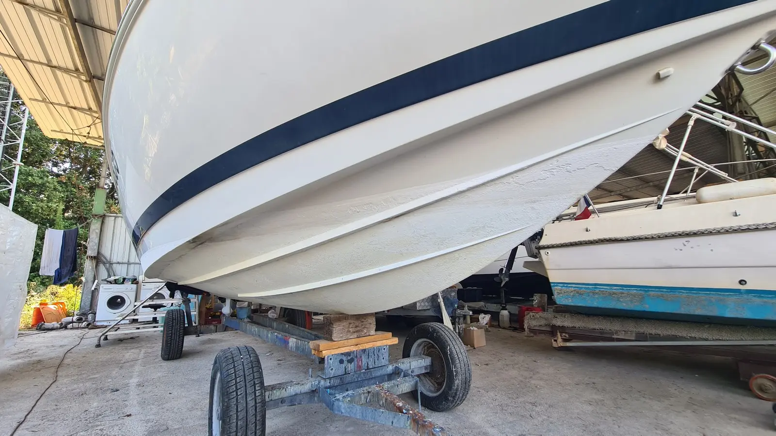 Chris Craft 210 — Vue rapprochée de la coque blanche d’un bateau posé sur une remorque.