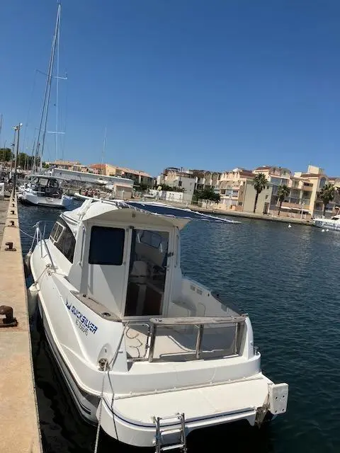 Quicksilver Activ 640 Weekend — Bateau à moteur blanc amarré dans un port, vu de trois quarts arrière.