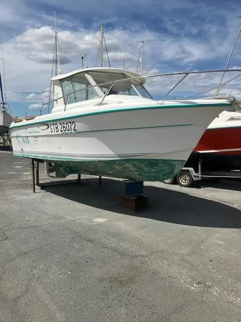 Ocqueteau 645 — Bateau à moteur blanc à cabine, posé sur sa remorque dans un port à sec.