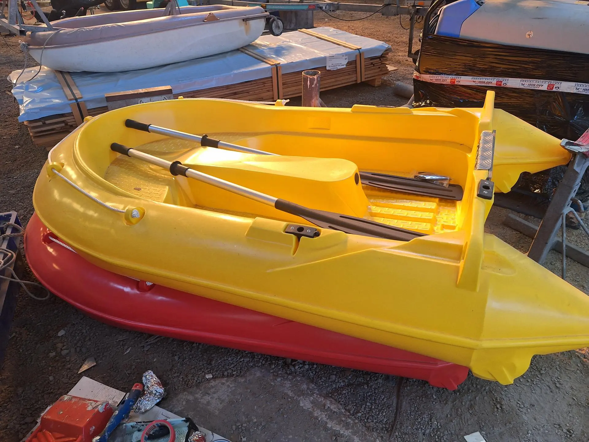 Armor Aviron Neptea 220 — Petite embarcation jaune équipée de rames, photographiée dans une zone de stockage.