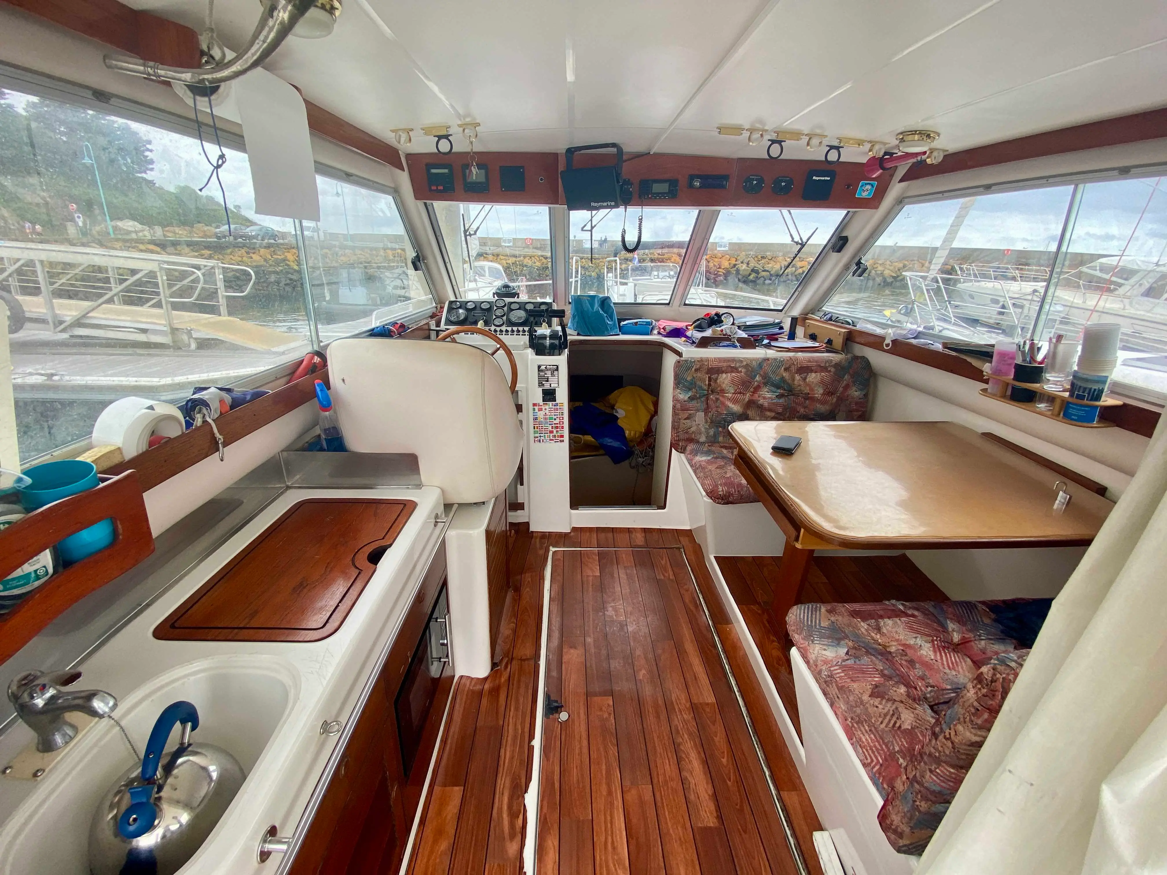 Rodman 1100 — Vue intérieure du carré avec poste de pilotage, banquette et coin cuisine.