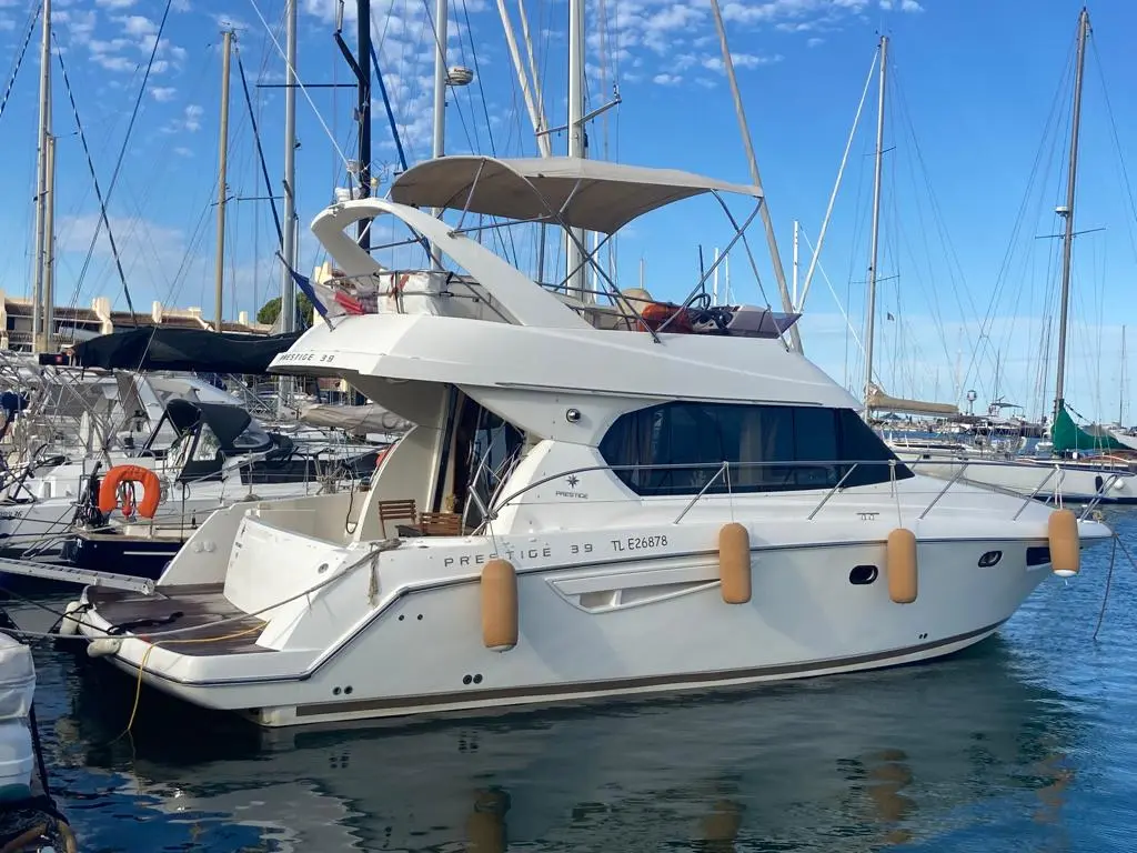 Jeanneau Prestige 39 — Bateau à moteur blanc de profil, amarré dans un port sous un ciel dégagé.