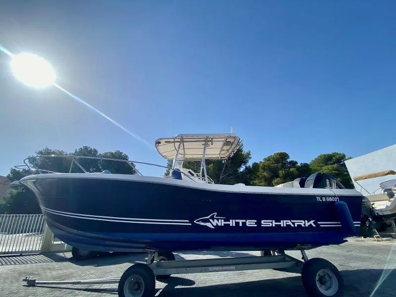 White Shark 285 — Bateau à moteur bleu et blanc présenté sur une remorque, vu de profil.