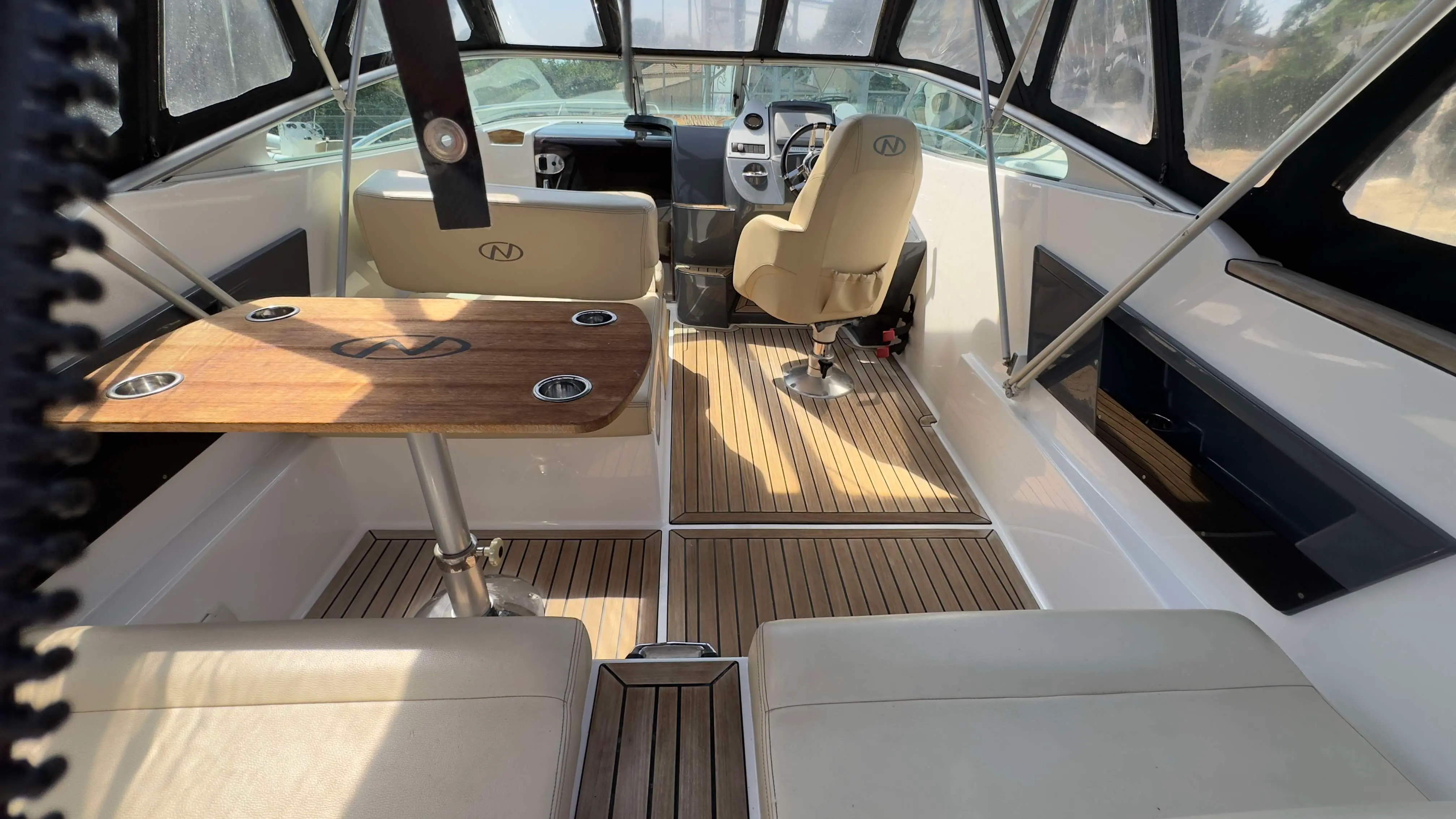 Nordkapp Noblesse 760 — Vue du cockpit couvert avec table, sièges et poste de pilotage.