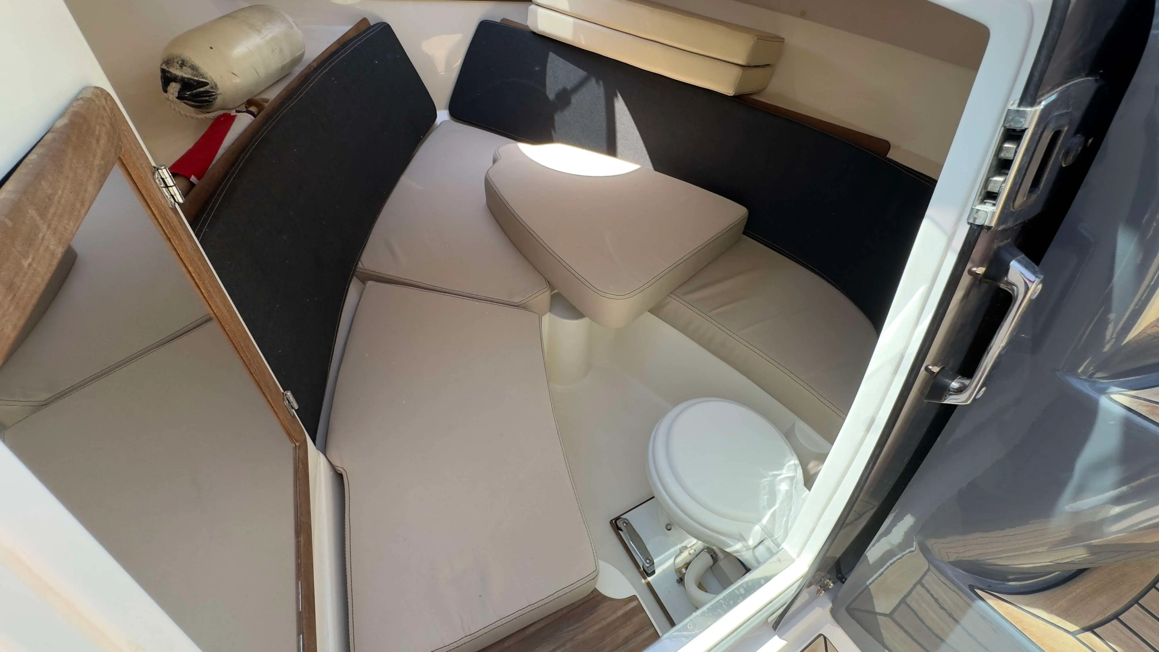 Nordkapp Noblesse 760 — Vue intérieure d’un bateau montrant une banquette, une table et un WC marin.