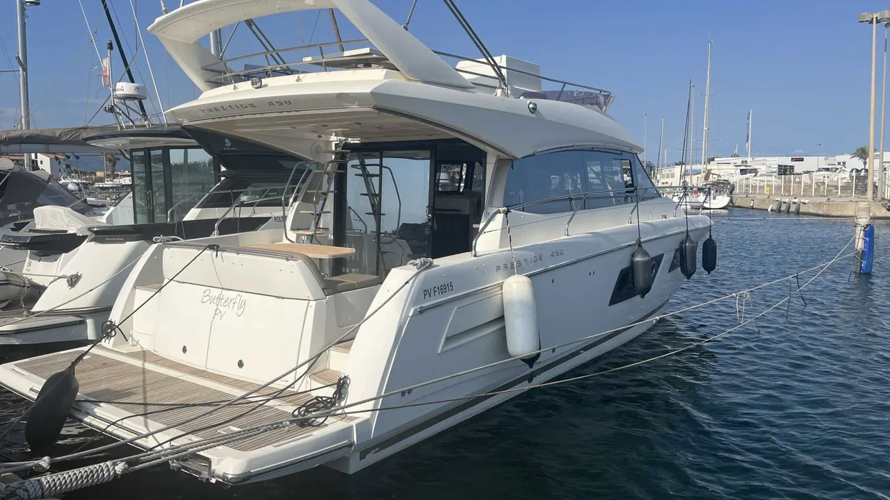 Jeanneau Merry Fisher 450 — Bateau à moteur blanc amarré dans un port, vu de trois quarts arrière.