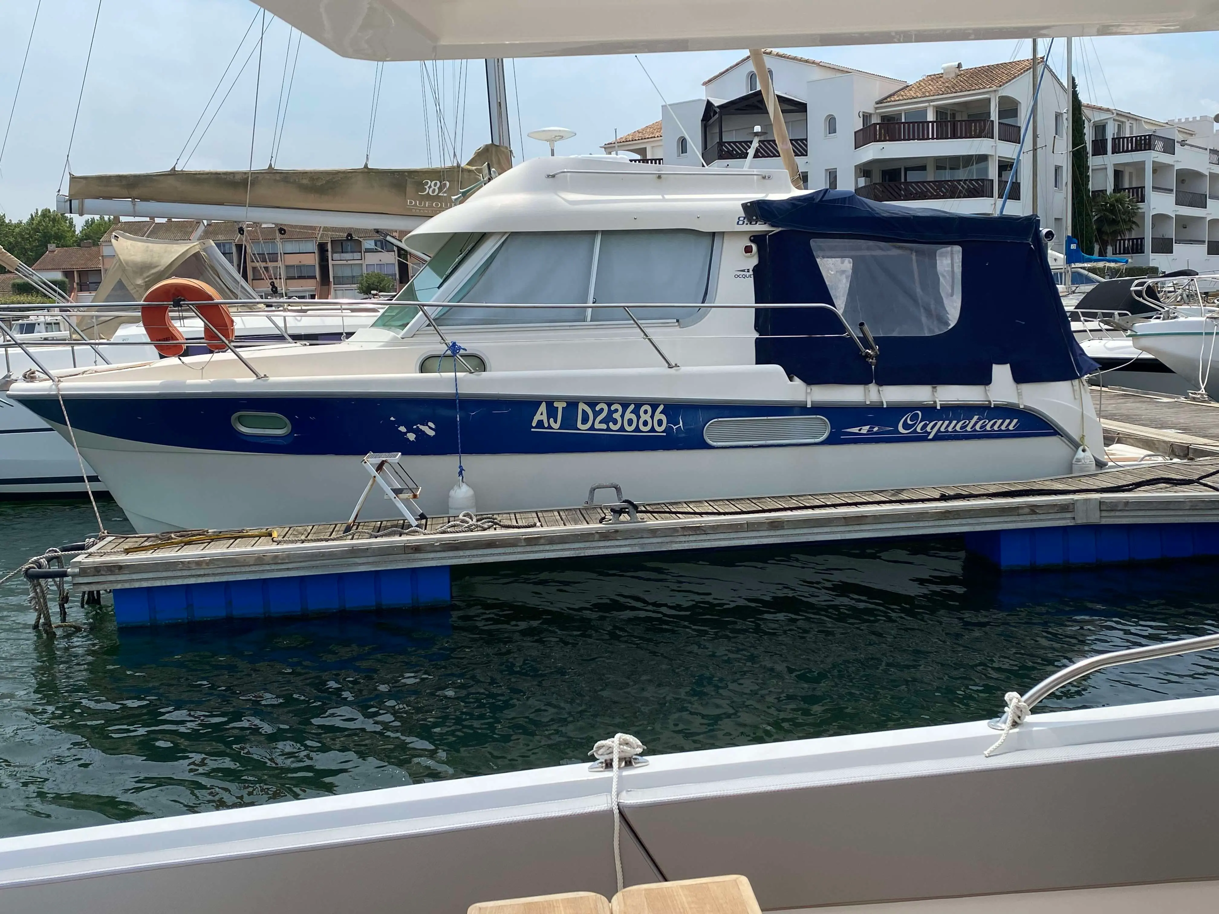 Ocqueteau 885 — Bateau à moteur amarré au ponton, vu de profil dans une marina.