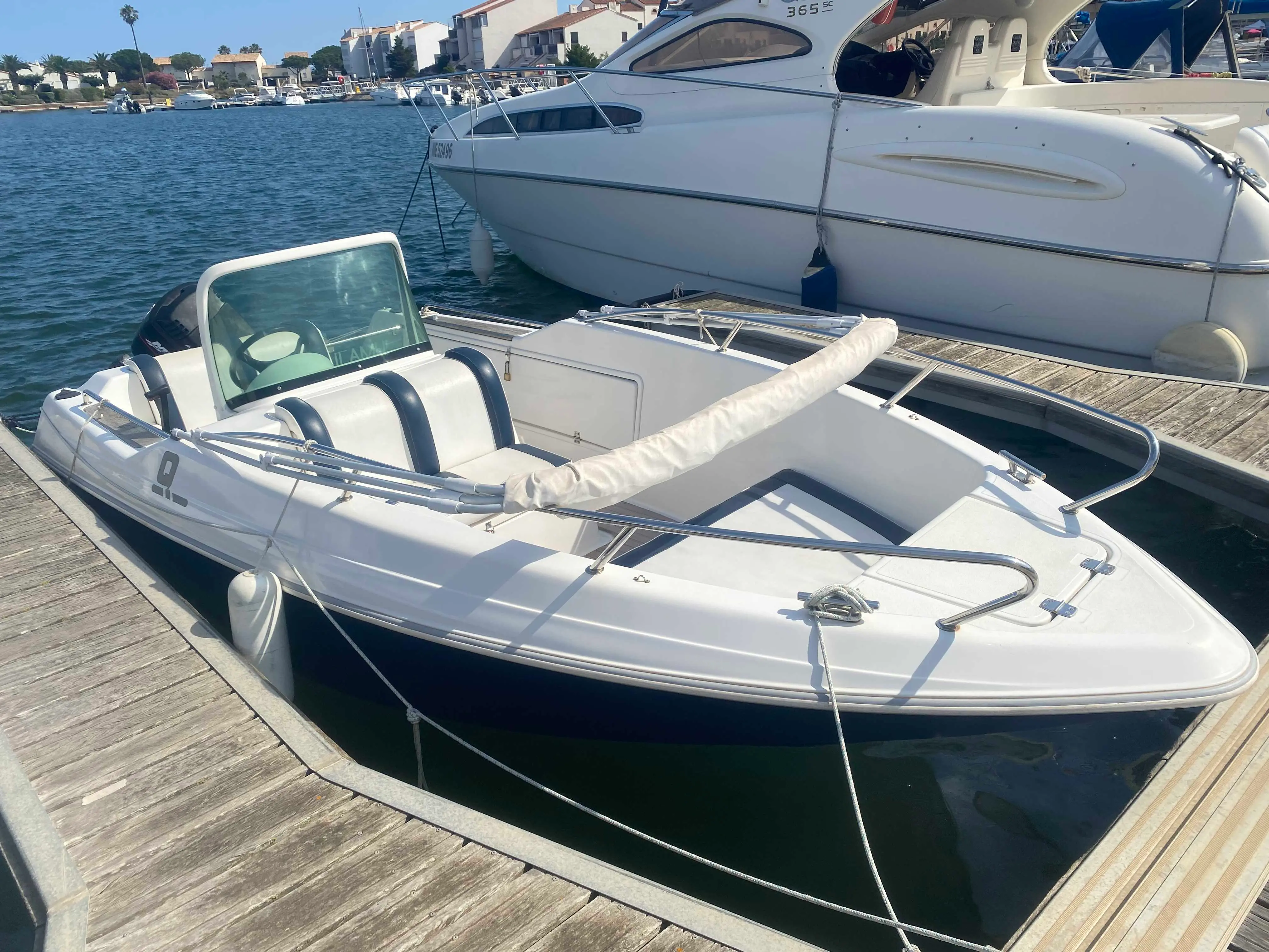 Quicksilver 500 Commander — Bateau à moteur blanc amarré à un ponton, vu de trois quarts avant.