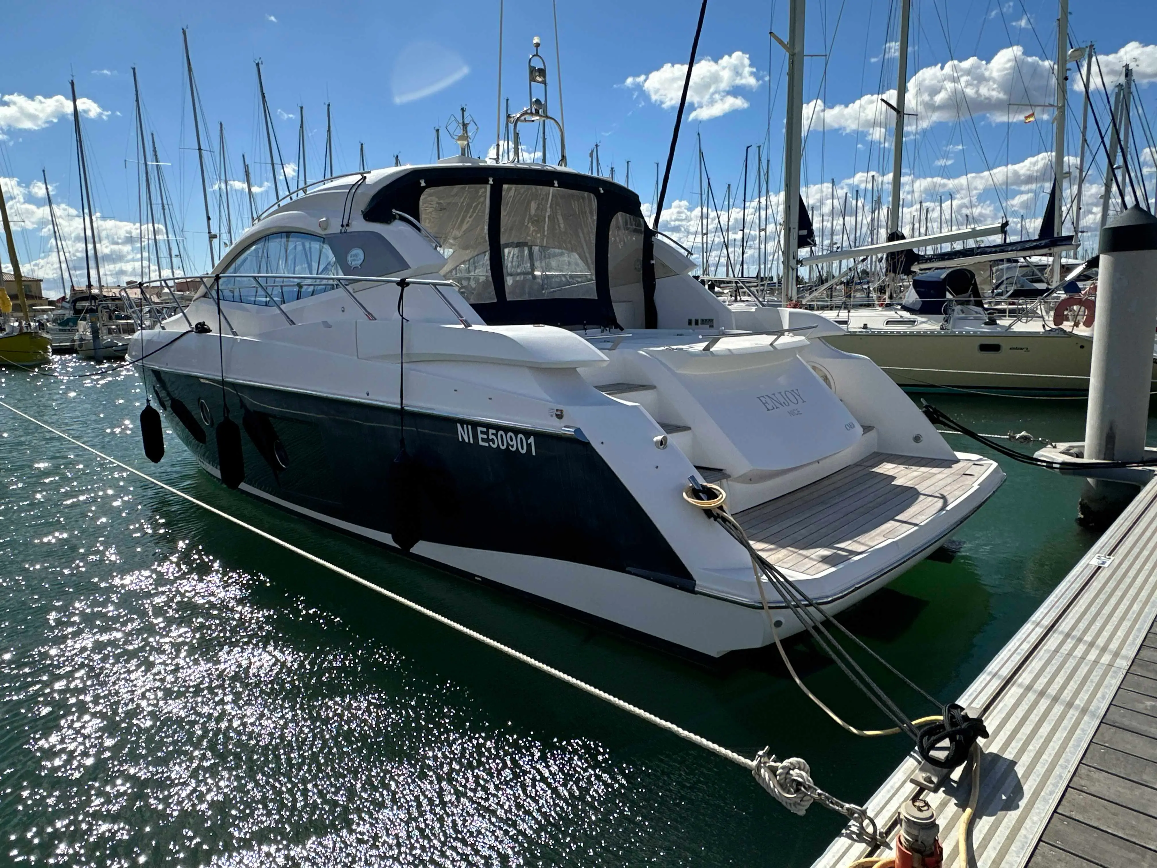 Sessa Marine C43 — Bateau à moteur blanc et bleu amarré dans un port de plaisance, vue arrière trois-quarts.