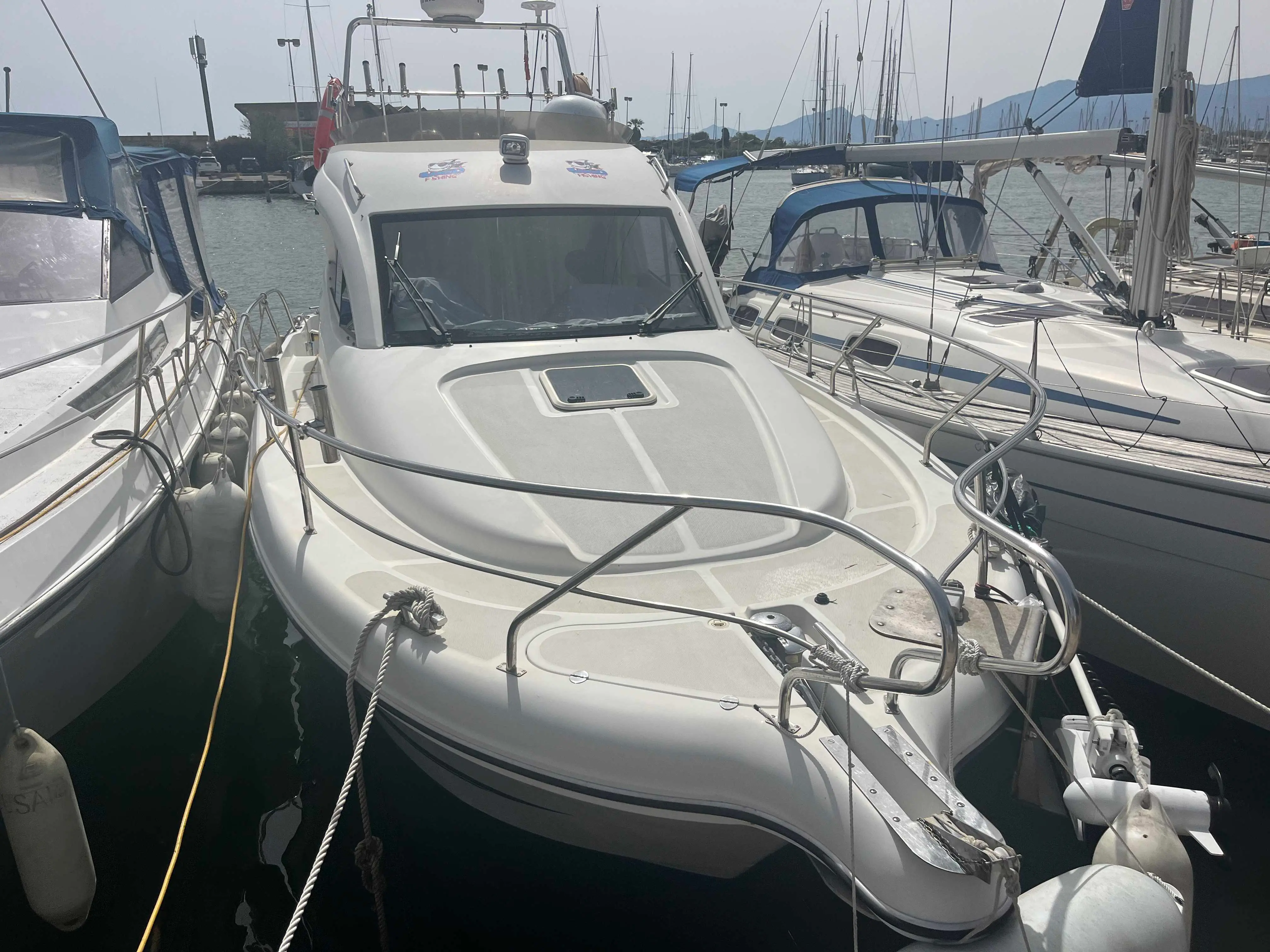 ST Boats Starfisher 30 Cruiser — Vue avant d’un bateau à moteur amarré dans un port, entre d’autres embarcations.