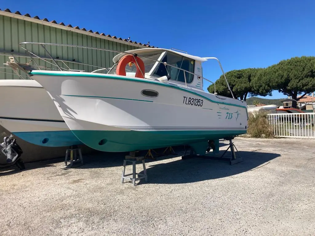 Ocqueteau 715 — Bateau à moteur blanc et turquoise présenté à terre, vu de trois quarts avant.