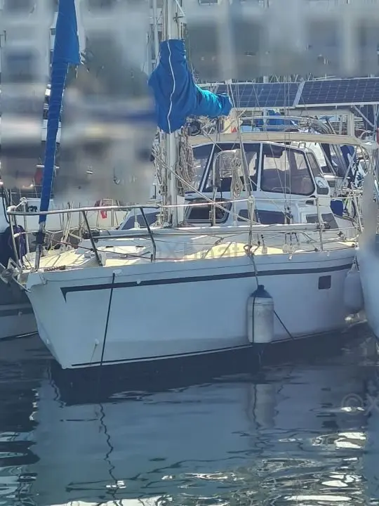 Scorpion 9 — Voilier blanc amarré dans un port, vu de trois quarts avant.
