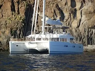 Lagoon 620 — Catamaran blanc et gris amarré devant une paroi rocheuse.