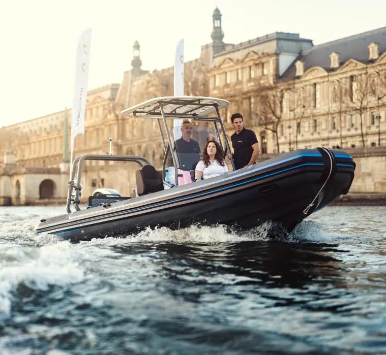 Highfield SP 760 — Bateau semi-rigide noir et bleu naviguant devant des bâtiments historiques.