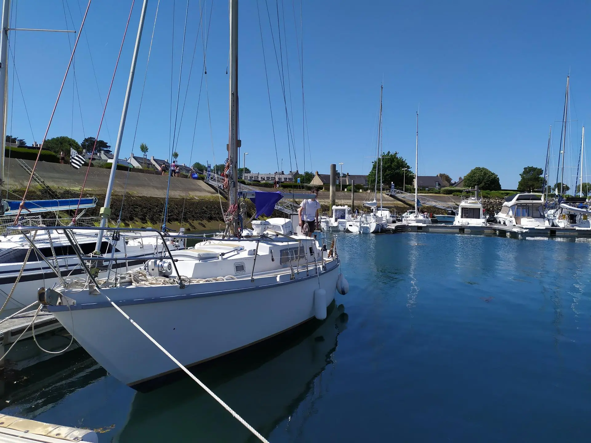Amel Kirk — Voilier blanc amarré dans un port, entouré d'autres bateaux.