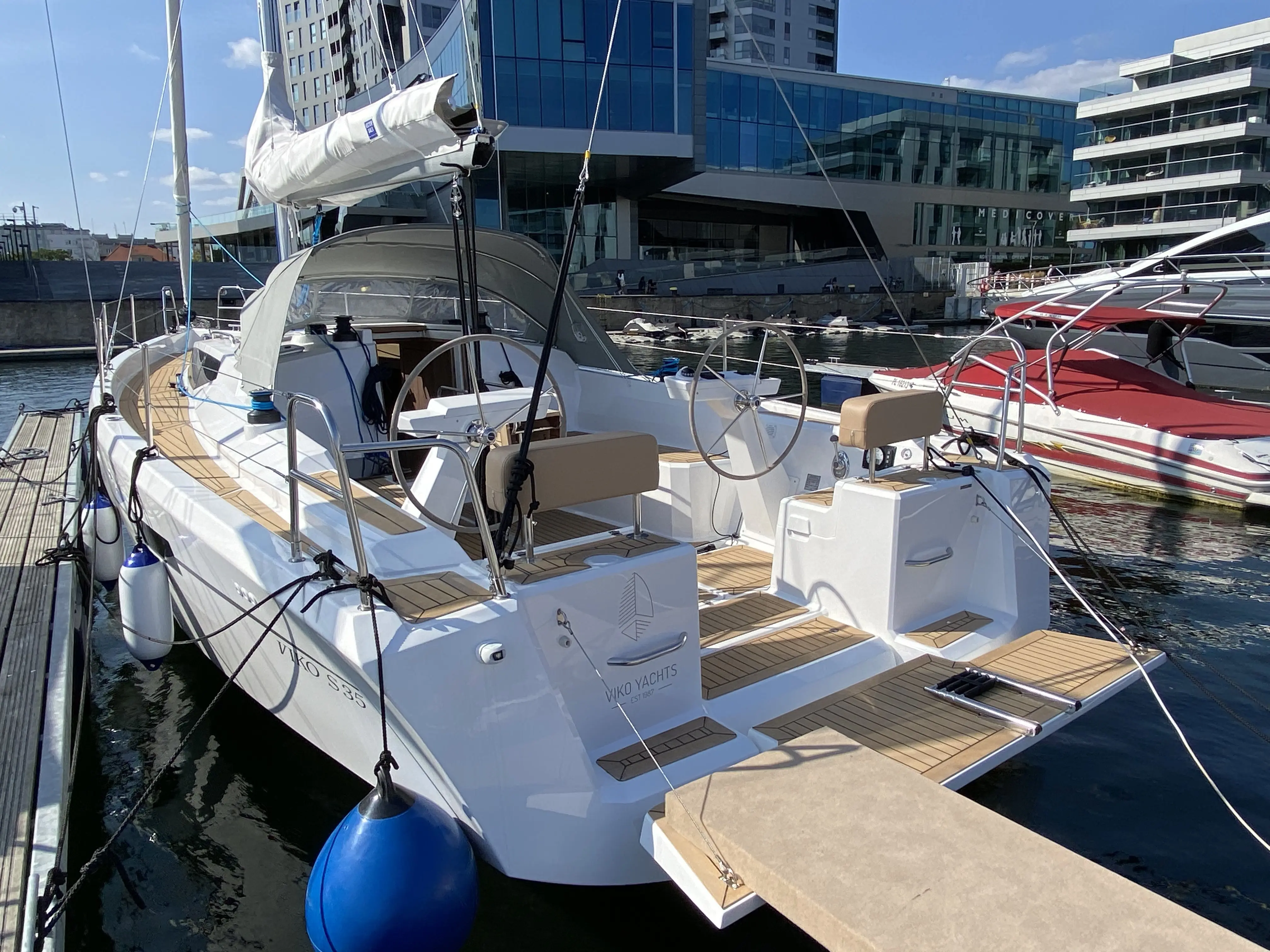 Viko Boats Viko 35 S — Voilier vu de trois quarts arrière dans une marina, avec cockpit et plateforme de bain.