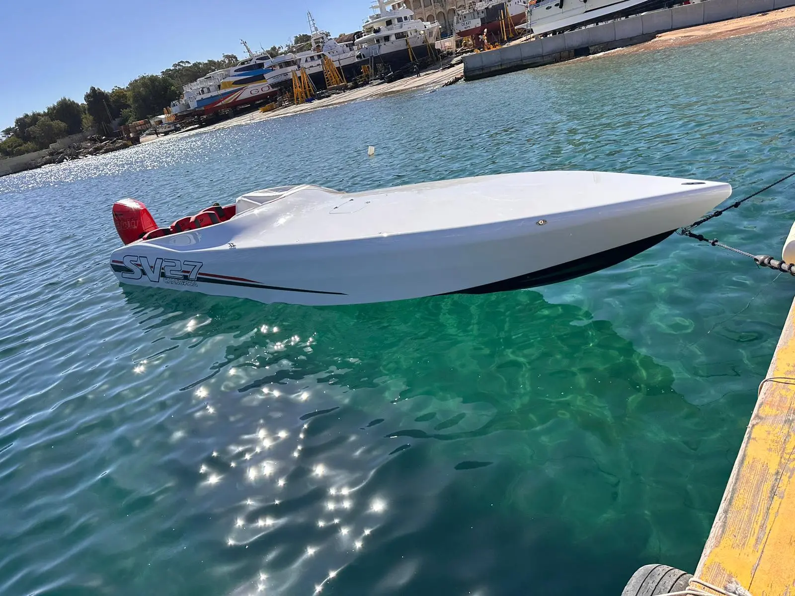 Chaudron Sv 27 Race Edition — Bateau blanc amarré sur une eau turquoise devant un chantier naval.