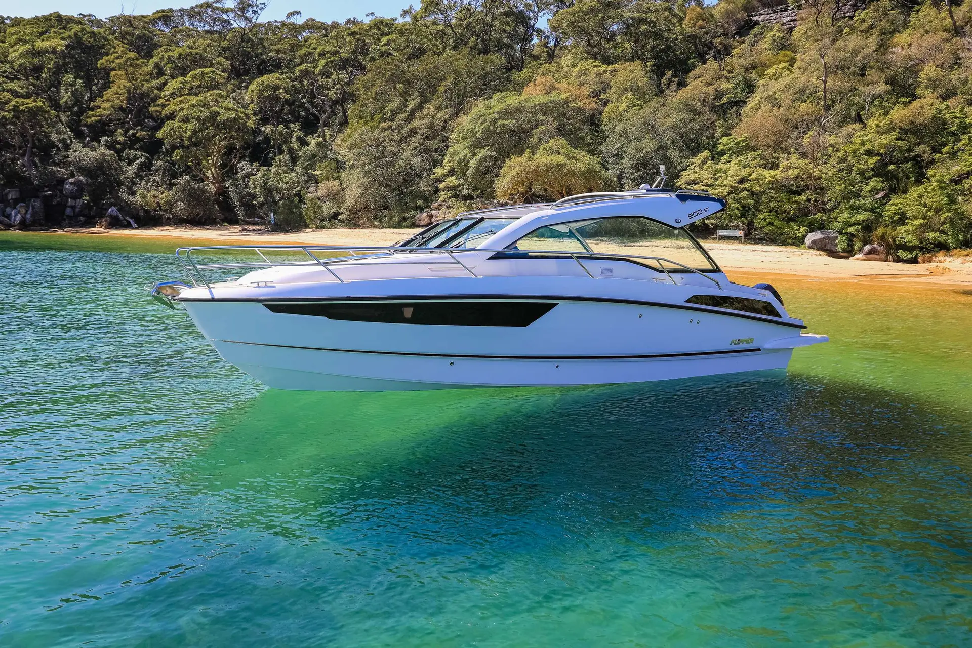 Flipper 900 ST — Bateau à moteur blanc photographié de profil dans une baie aux eaux turquoise.