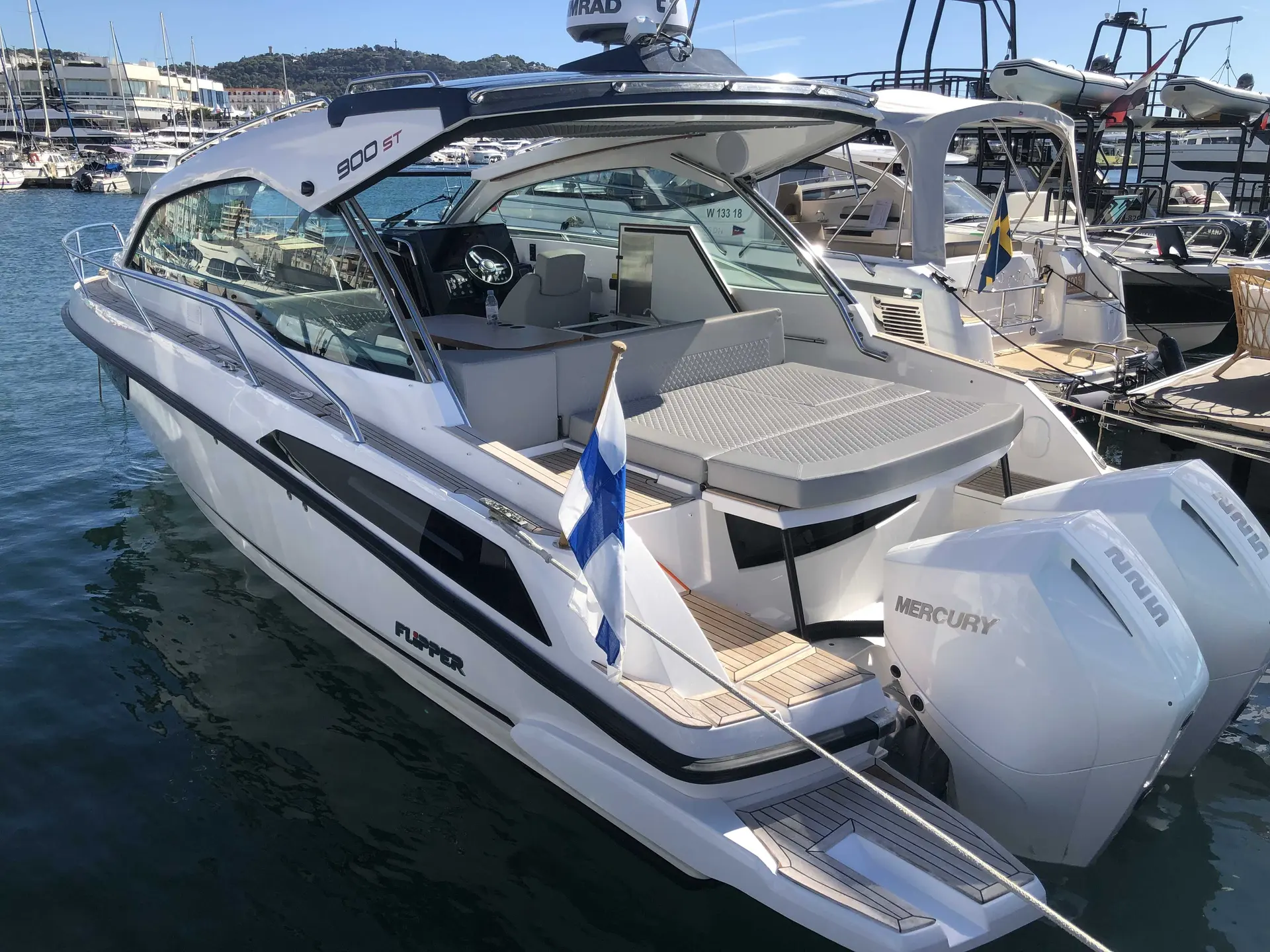 Flipper 900 ST — Bateau à moteur blanc vu de trois quarts arrière dans un port, avec deux hors-bord.