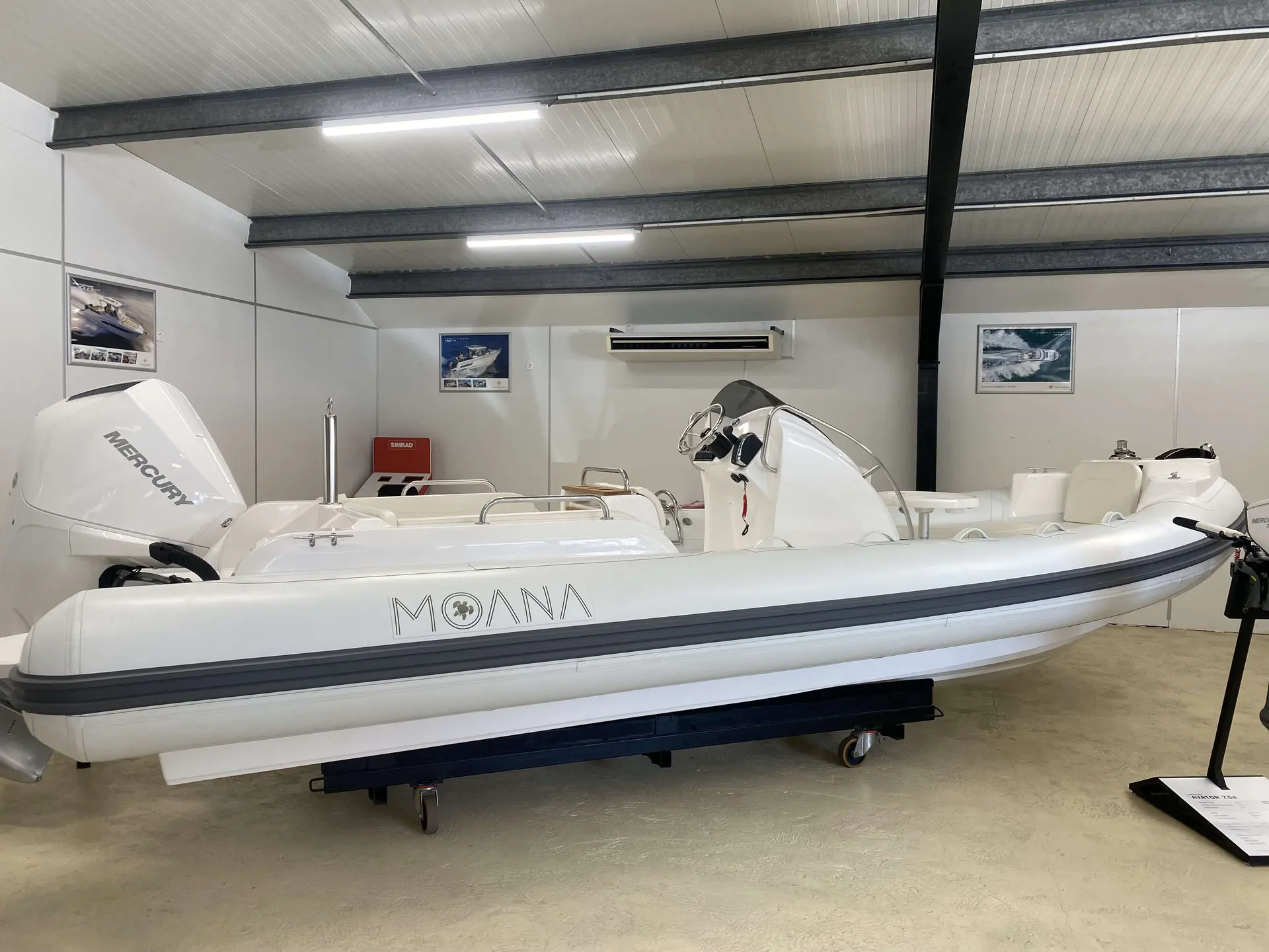 Moana 700 — Bateau pneumatique blanc exposé en intérieur, vu de profil, avec moteur hors-bord.