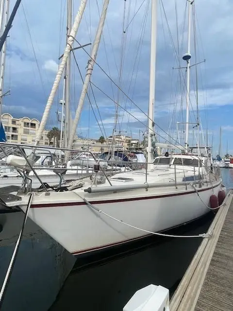 Amel Maramu — Voilier blanc amarré dans une marina, vu de trois quarts avant.