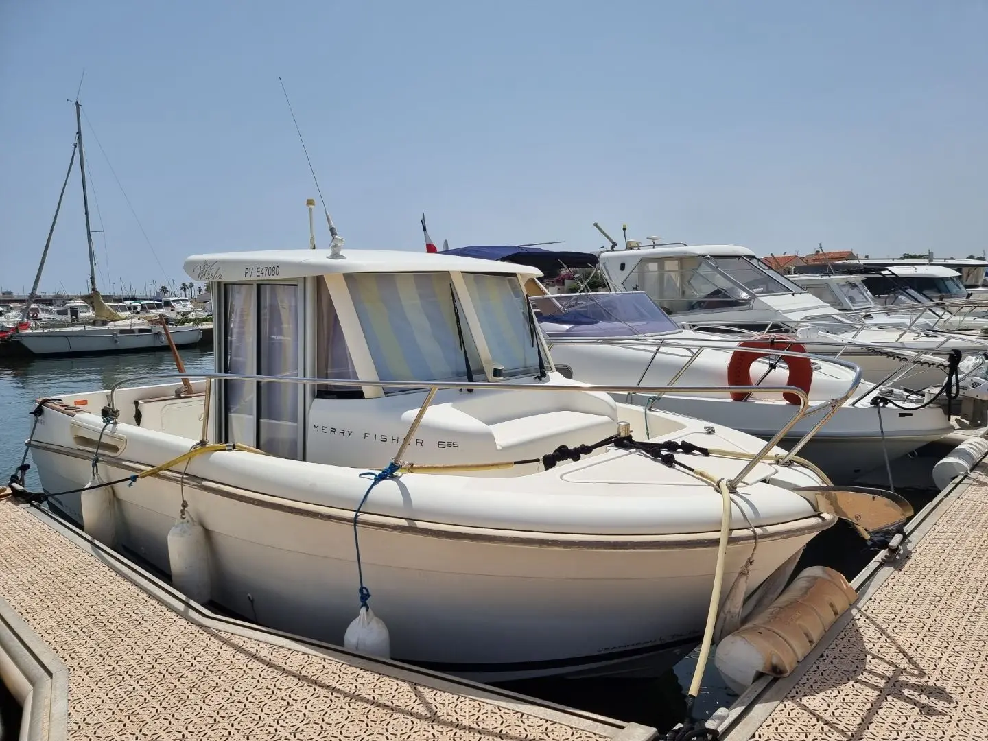 Jeanneau Merry Fisher 655 — Bateau à moteur blanc portant l'inscription Merry Fisher 695, amarré dans un port.