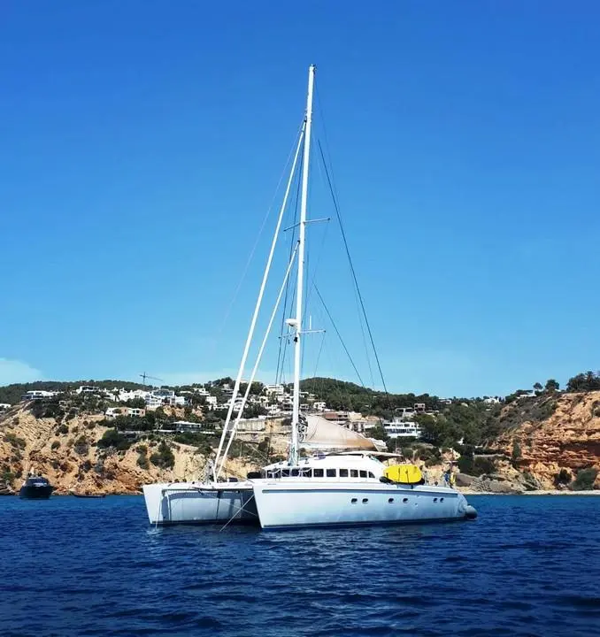 Lagoon 57 — Catamaran blanc au mouillage devant une côte rocheuse ensoleillée.