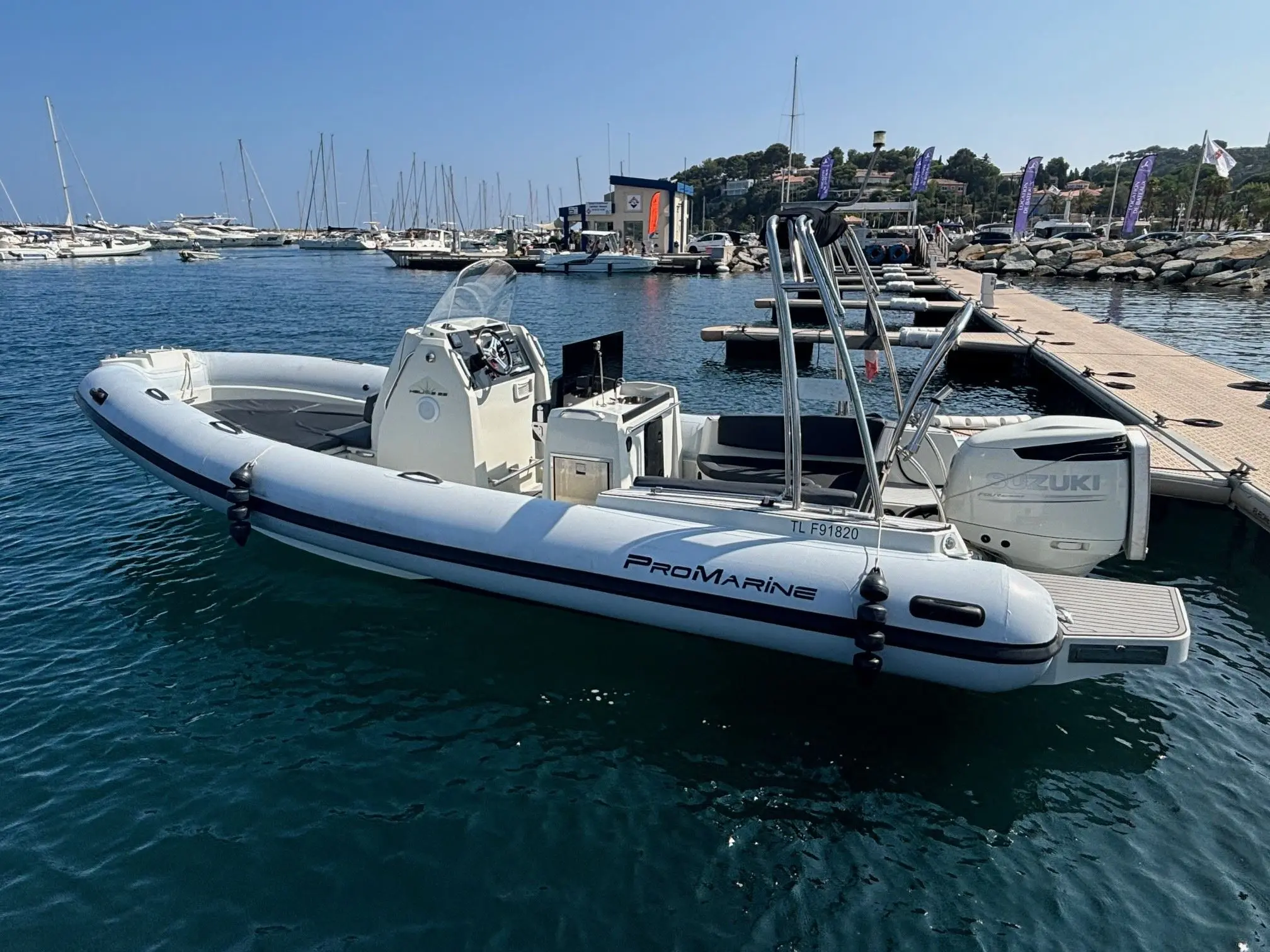 Pro Marine Helios 25 — Bateau semi-rigide blanc amarré dans un port, vu de trois quarts.