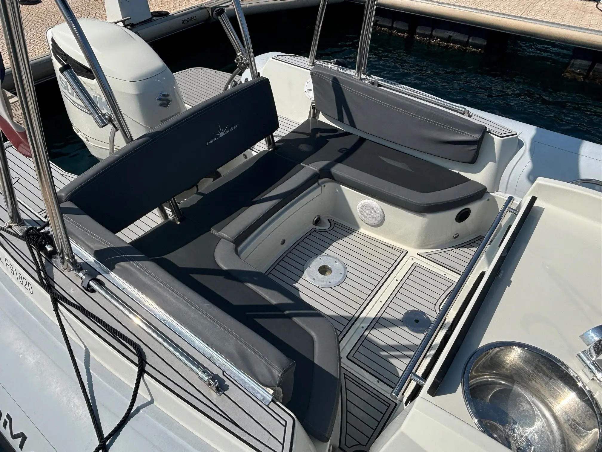 Pro Marine Helios 25 — Vue du cockpit arrière avec banquettes, moteur hors-bord et plage de baignade.