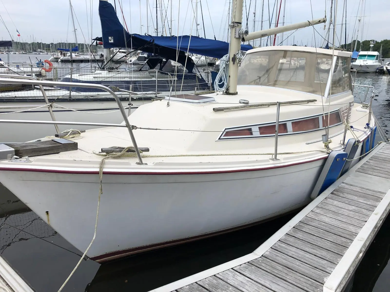 Beneteau Evasion 25 — Voilier blanc amarré à un ponton dans une marina, vu de trois quarts.