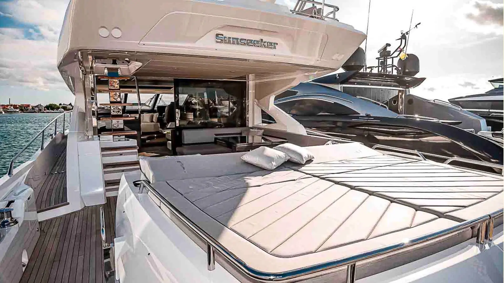 Sunseeker Sport Yacht 74 — Vue extérieure d’un yacht à moteur avec bain de soleil avant et cockpit arrière.