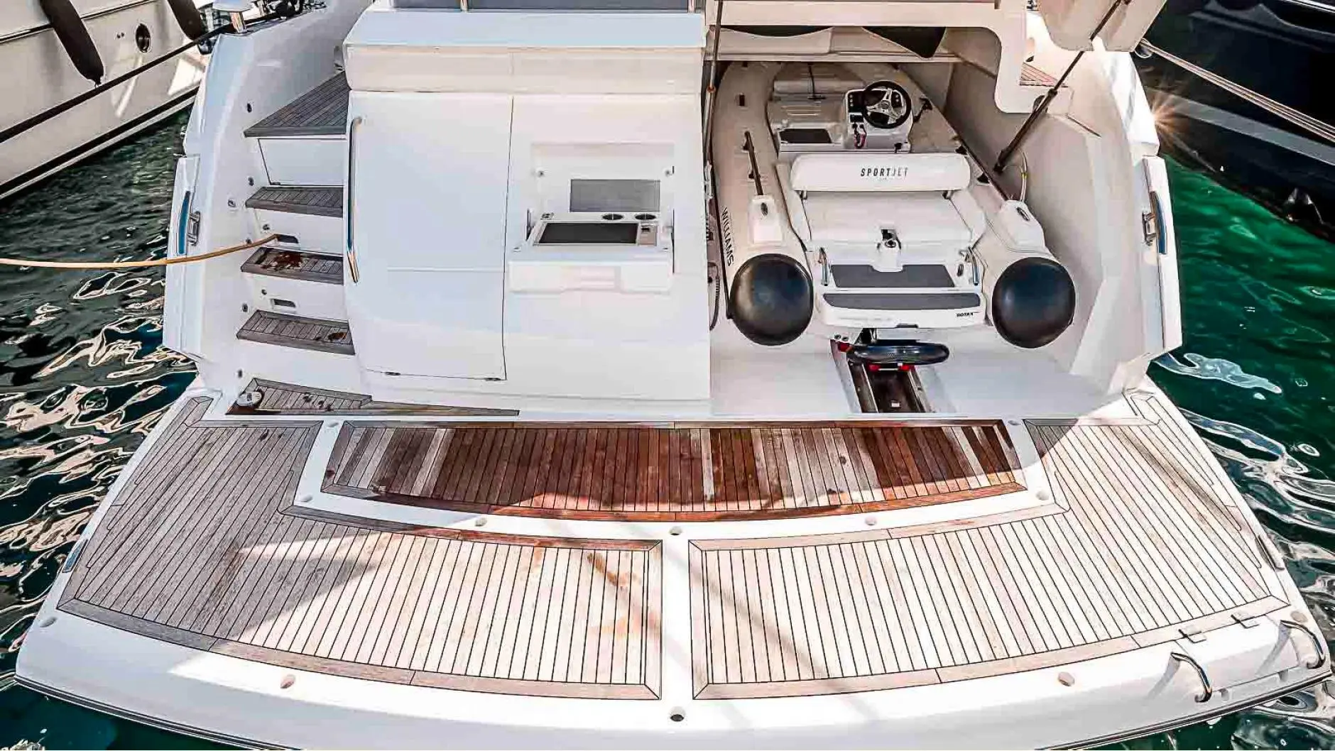 Sunseeker Sport Yacht 74 — Vue plongeante de la plage arrière et du tender d’un bateau amarré.