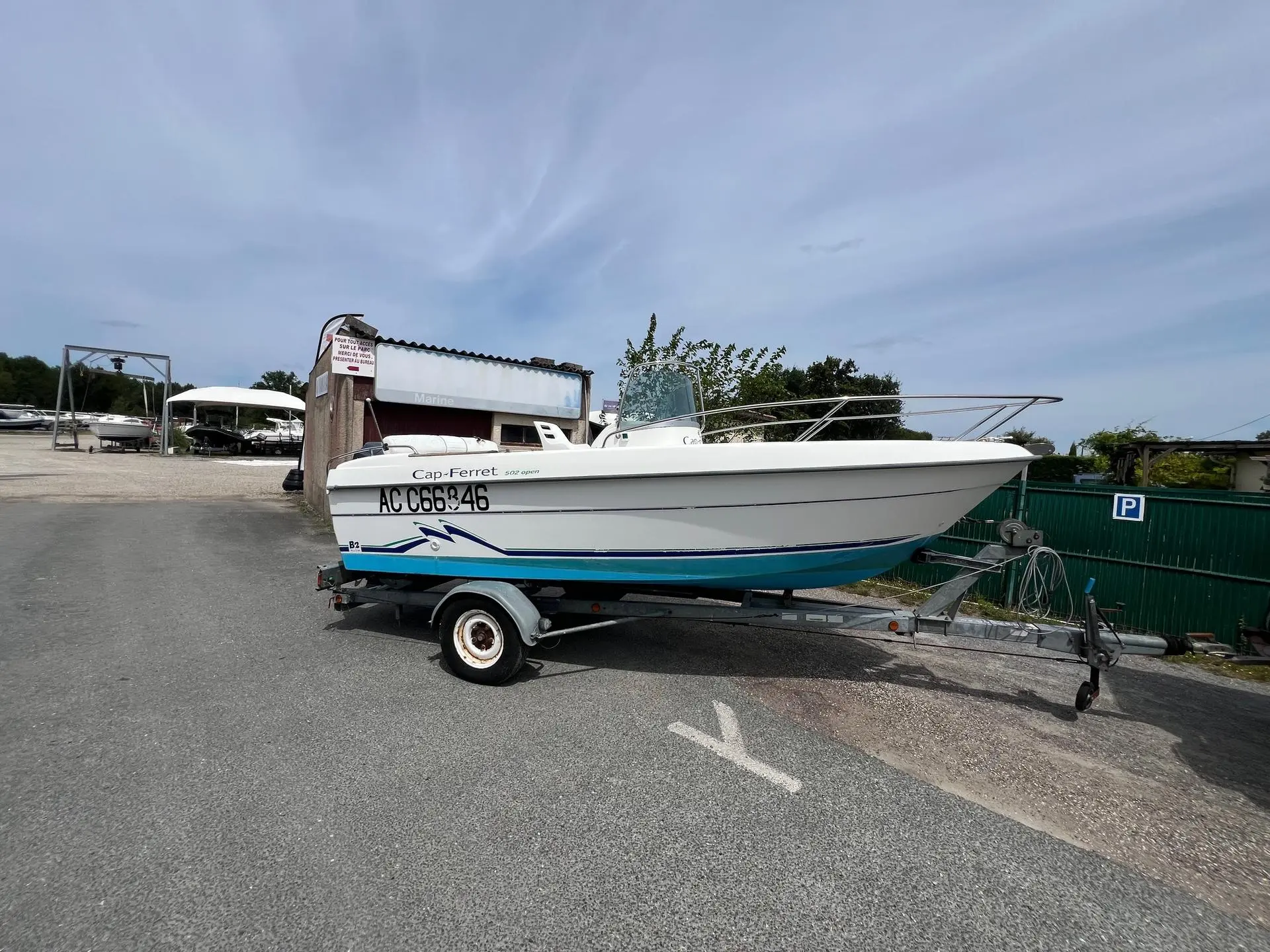 B2 Marine 502 — Bateau blanc et bleu sur remorque, photographié de trois quarts à terre.