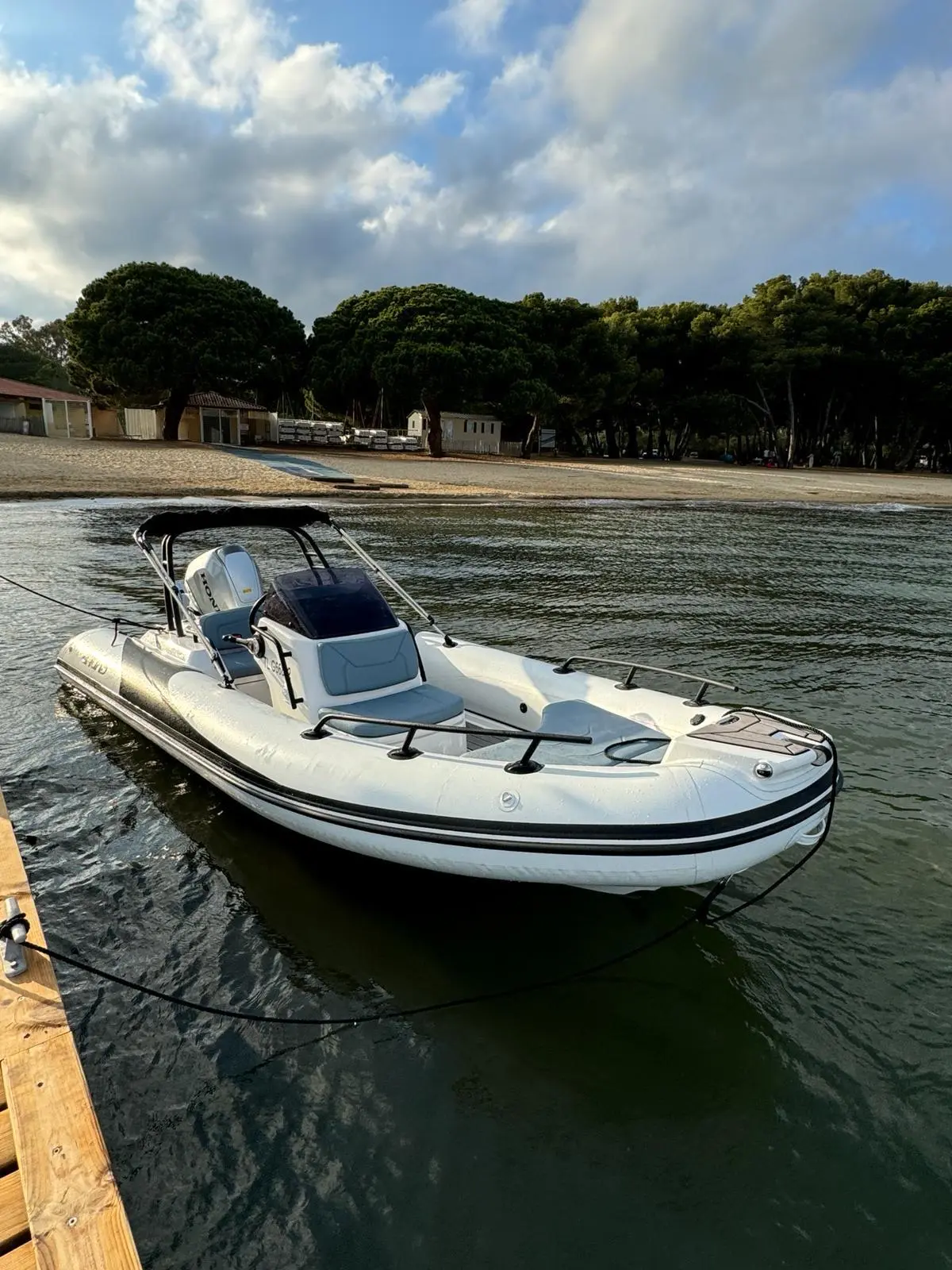 Grand Golden Line G500 — Bateau pneumatique à console et moteur hors-bord amarré près d'une plage.