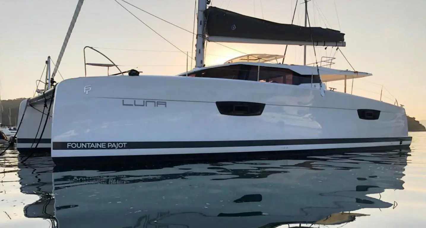 Fountaine Pajot Saona 47 — Vue latérale d’un catamaran blanc amarré, photographié au ras de l’eau.
