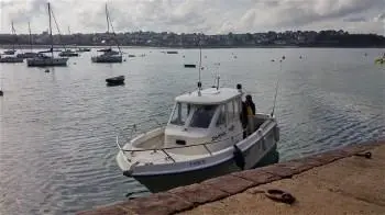 Guymarine Antioche 700 IB LA — Bateau à moteur amarré au bord d’un plan d’eau, vu de trois quarts avant.