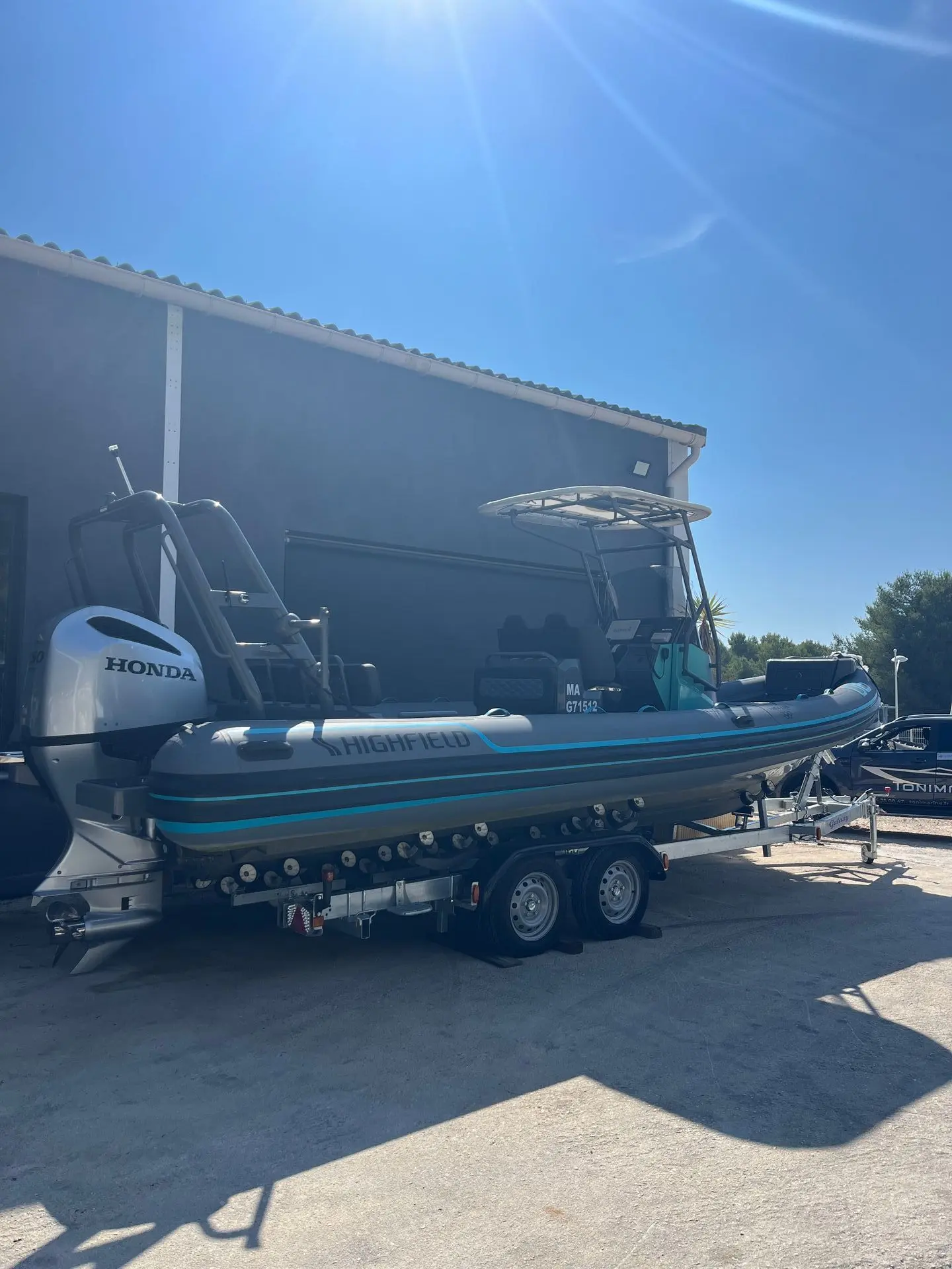 Highfield SP 760 — Bateau semi-rigide bleu et gris présenté sur sa remorque devant un bâtiment.