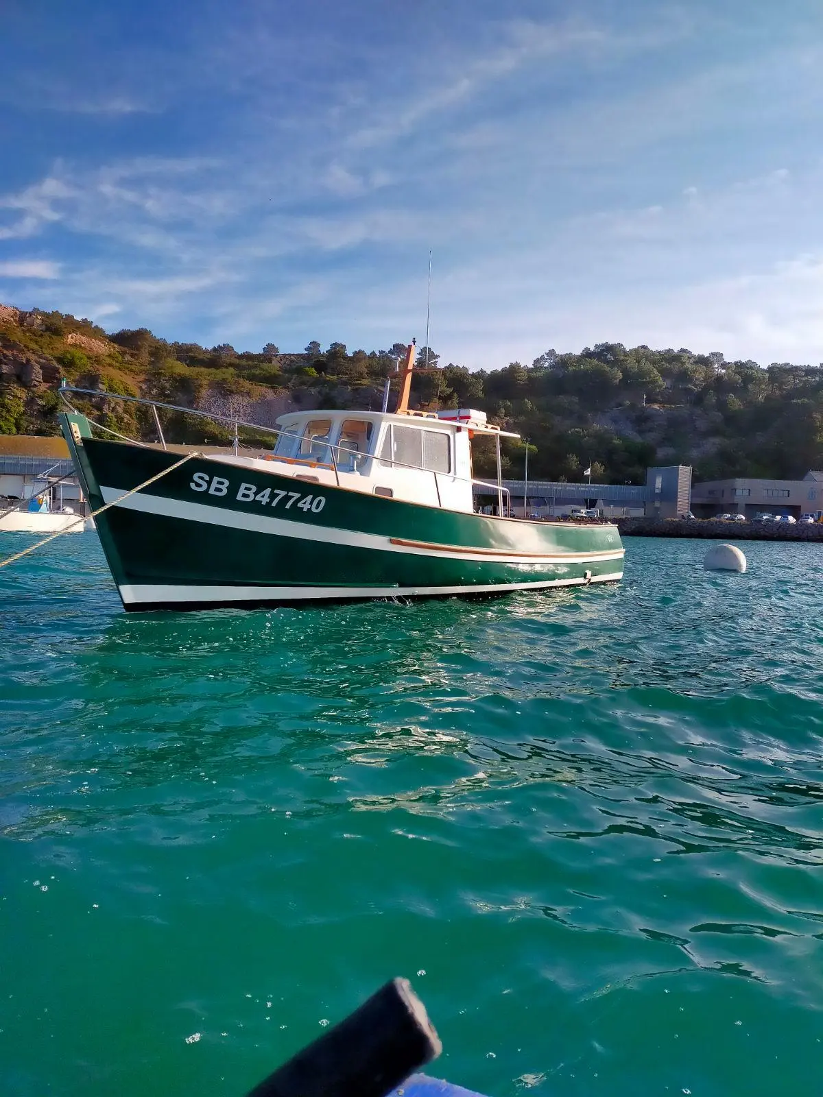 Rhea 900 — Bateau de pêche vert et blanc vu au mouillage près d’une côte rocheuse.