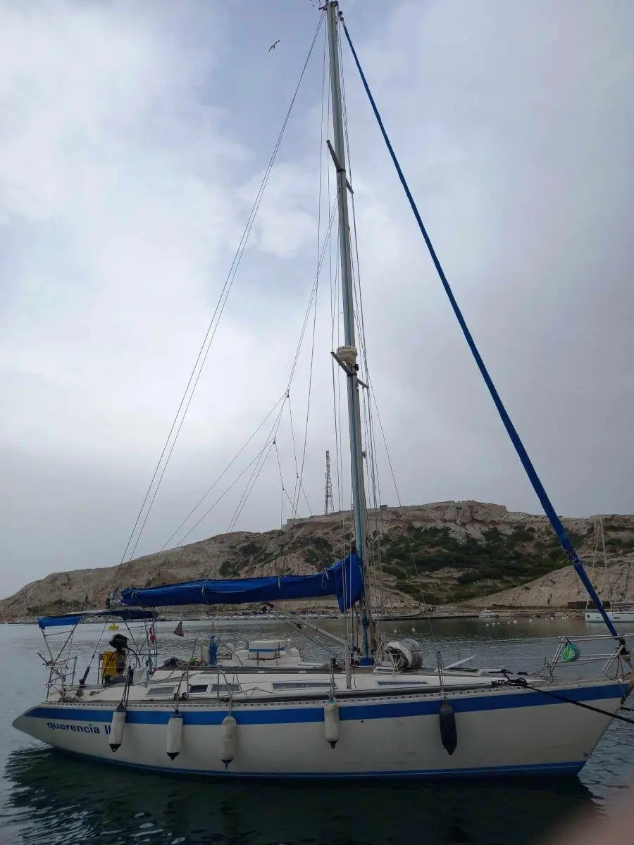 Wauquiez Centurion 38 — Voilier amarré dans une crique, photographié de profil avec sa grand-voile ferlée.