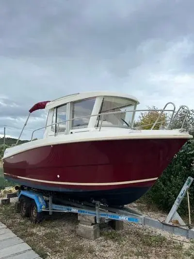 Jeanneau Merry Fisher 6 Marlin — Bateau à moteur rouge et blanc posé sur une remorque, photographié à terre.