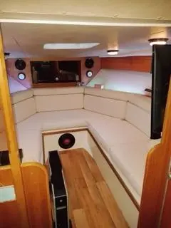 Riviera PRINCESS 286 — Salon intérieur d’un bateau avec banquette en U, table centrale et équipement audio.