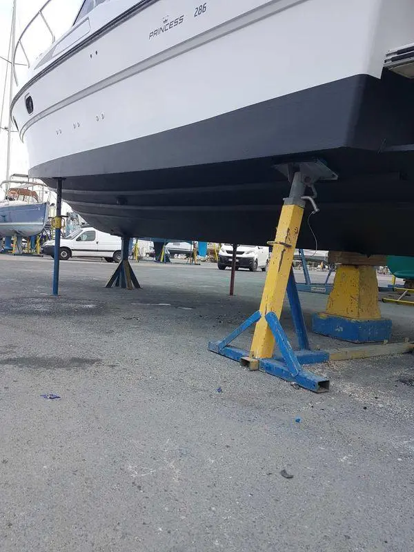 Riviera PRINCESS 286 — Vue partielle de la coque d’un bateau sur bers dans un chantier naval.