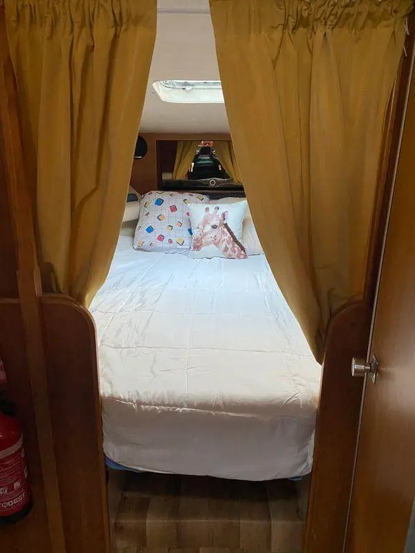 Riviera PRINCESS 286 — Cabine avec lit double, rideaux ouverts et hublot visible.