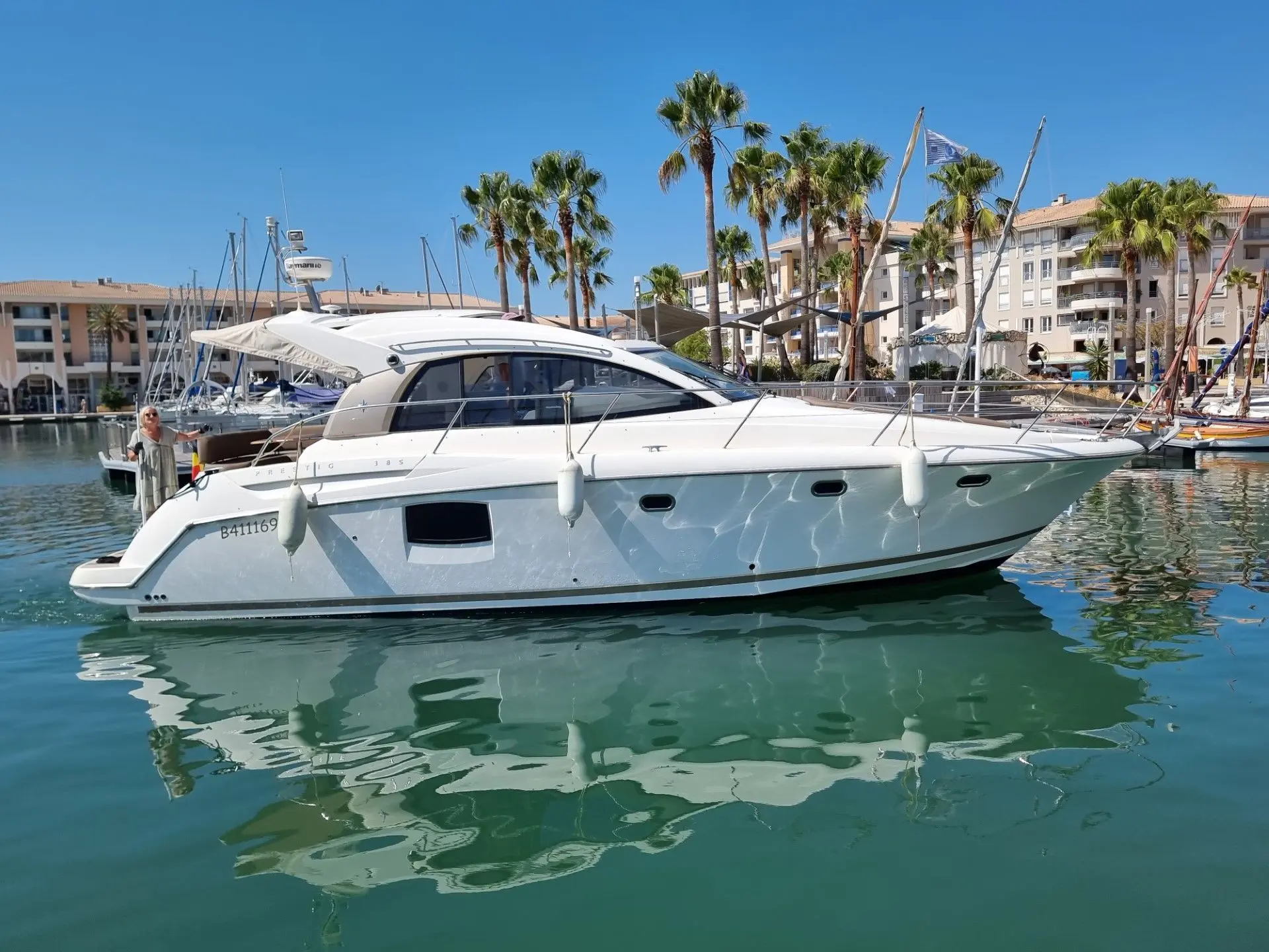Jeanneau Prestige 38 — Bateau à moteur blanc vu de profil dans une marina ensoleillée.